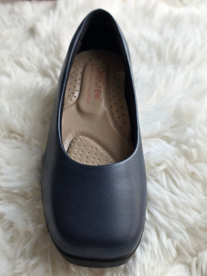Navy blue slip-on shoe with a visible brand logo on a white fluffy surface www.onlirew.com
onlycrew