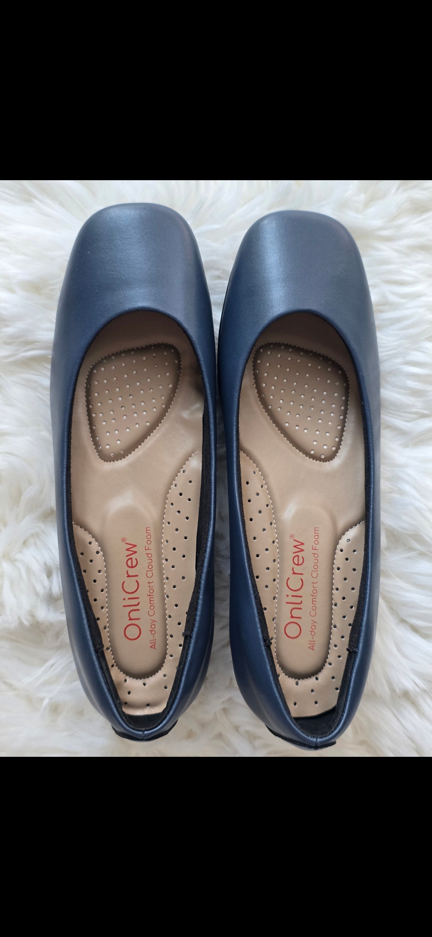 Pair of blue flats with visible brand name on a white fluffy surface + cloud foam navy blue cabin crew shoes + onlycrew onlicrew.com

